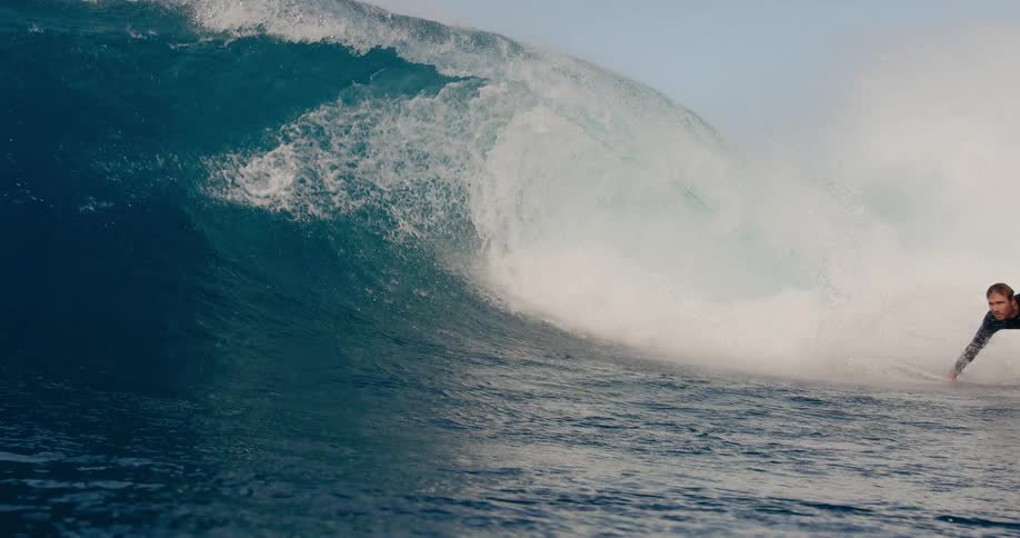 Young adult man surfing through a wave outdoors during day time