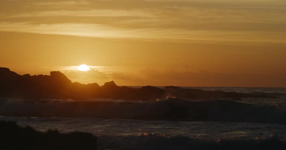 The sun is rising on the rough coast