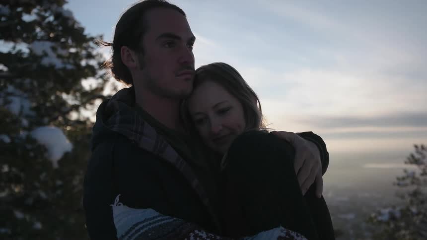 A man hugs a woman on a cloudy day