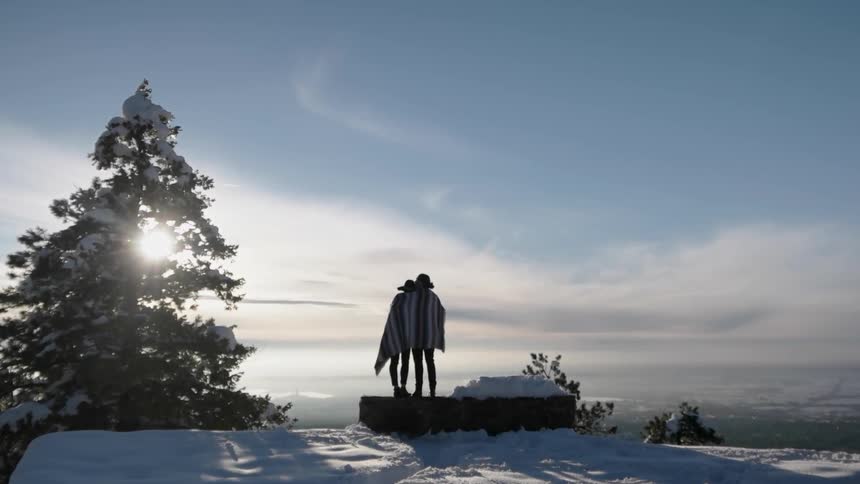 Two people stand on a cliff together