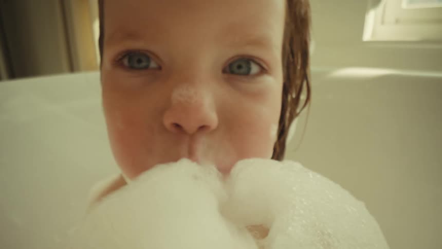 The baby blows bubbles in the bubble bath