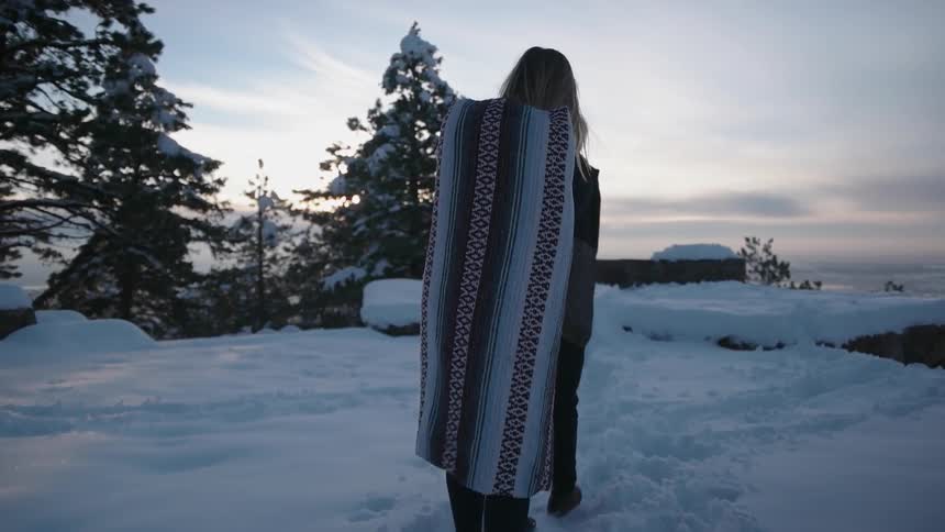 A man and woman walk toward a view on a snow-covered cliff