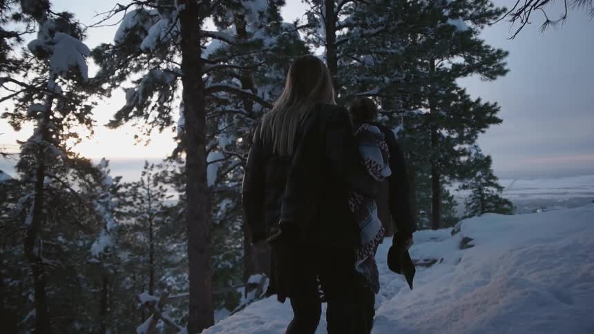 Two people hike in the snow on a hillside