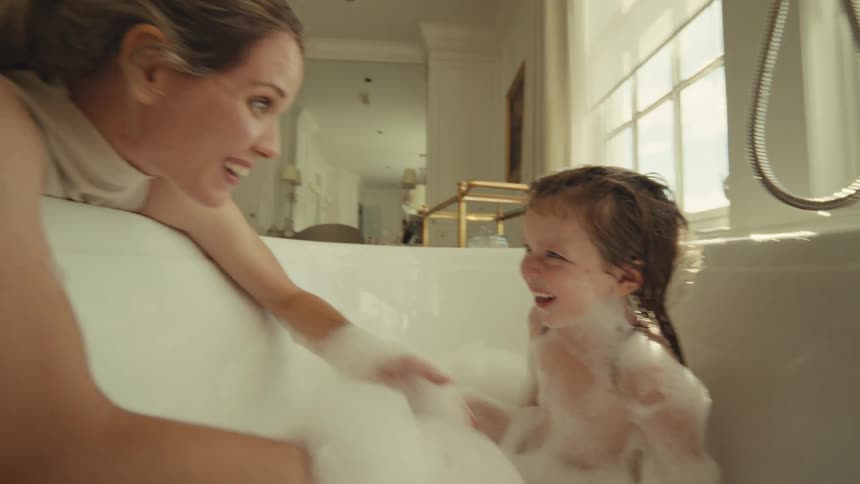Mother giving her daughter a bath in the bathtub