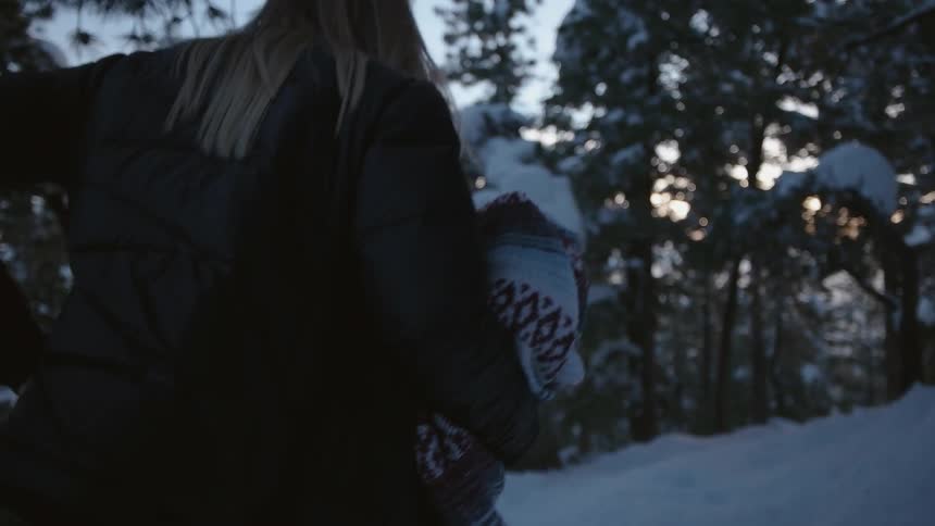 A man and woman walk through a snowy area with a blanket