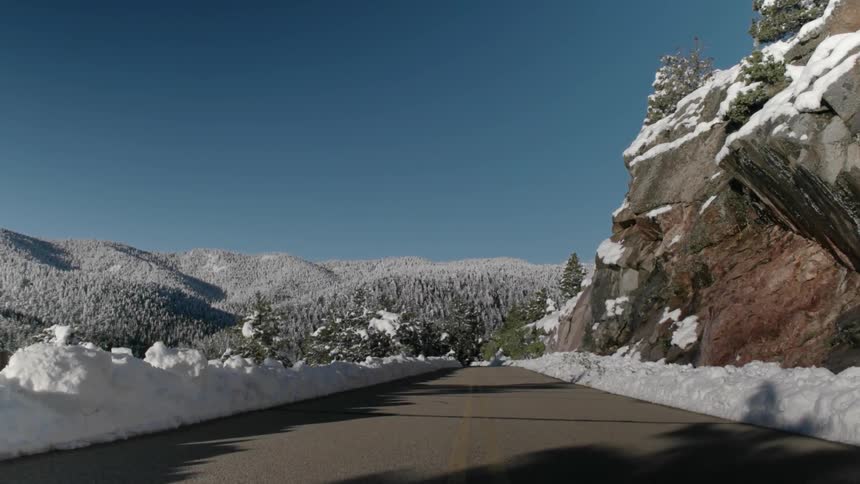 A road in the mountains is lined with snow