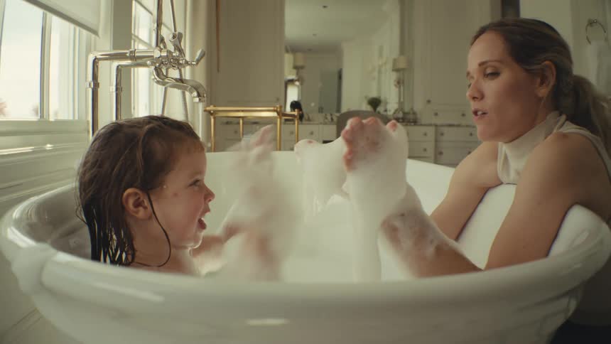 Young adult woman and little girl playing with the foam on a bathtub indoors during day time