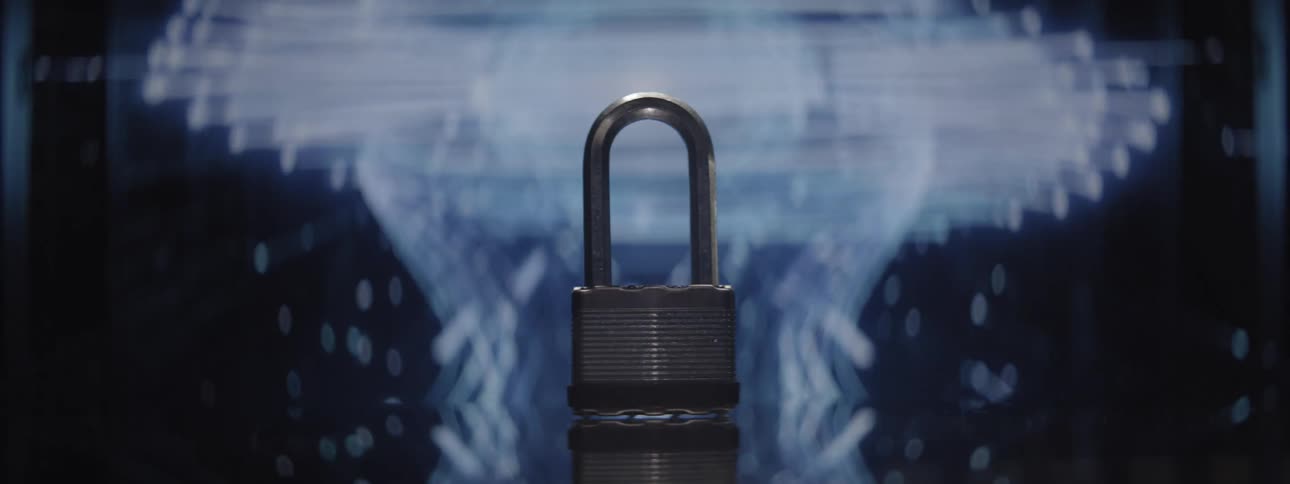Metal padlock in the foreground against a bluelit background