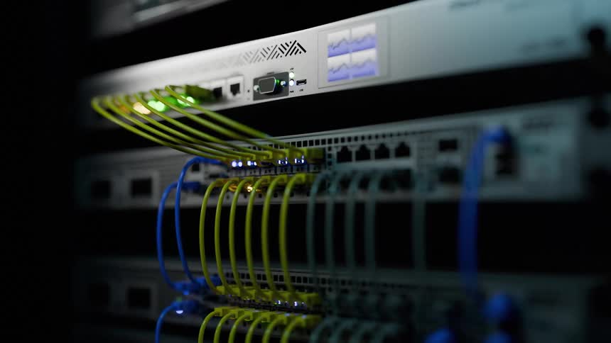 Yellow and blue cables connect network gear with active lights in server rack