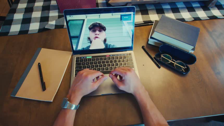 Person participating in a video call on a laptop over an organized desk