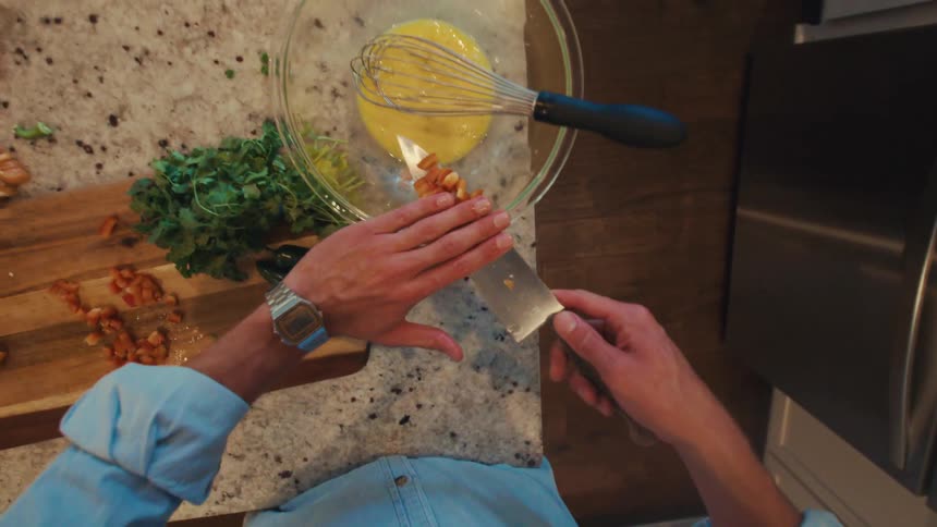 Person slices peppers and places them into a bowl containing an egg mixture