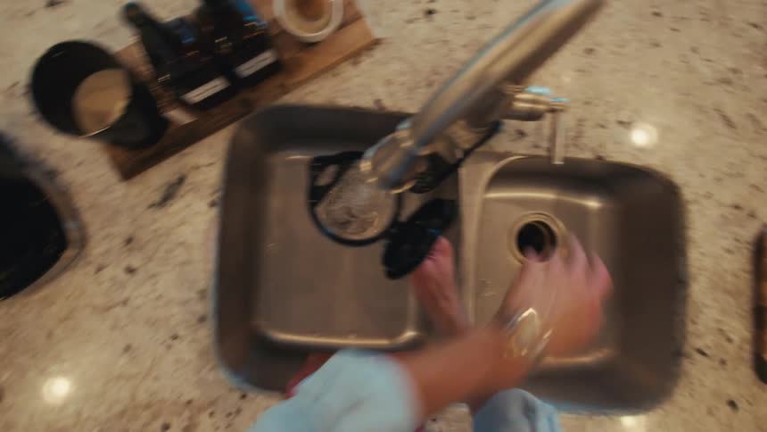 Person with wristwatch handles pod in coffee maker on granite countertop in modern kitchen
