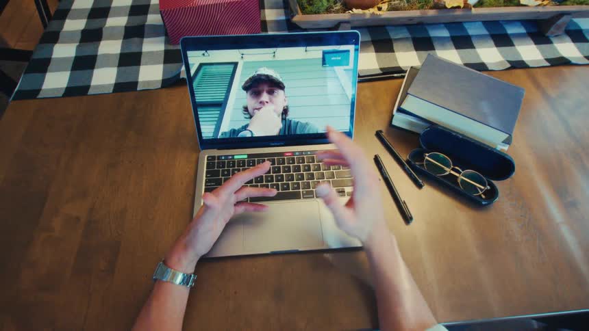 Man gestures during a laptop video call with another man