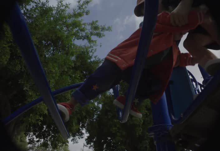 Older boy helps a younger boy while they play on playground equipment