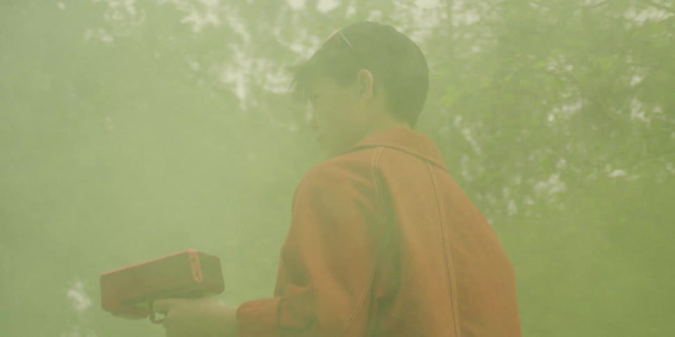 Smoke fills the air as a boy walks in his yard holding a toy gun