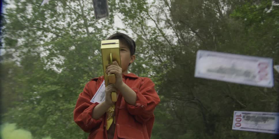 Child operating a goldcolored moneyshooting toy in a wooded area