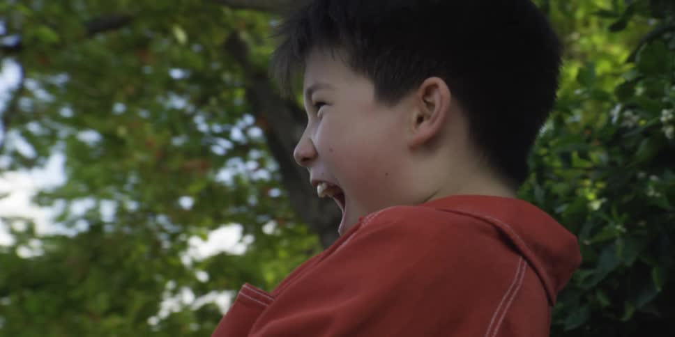 Boy holding a hose while a stream of water is directed outdoors