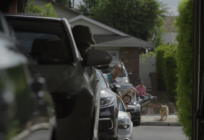 People looking out from car windows parked on a residential street