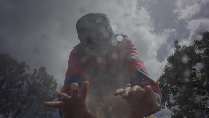 Boy in striped jacket extends his hands through a jet of water