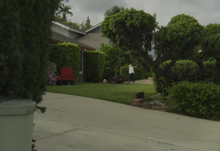 Boy pushing a lawn mower in a residential yard