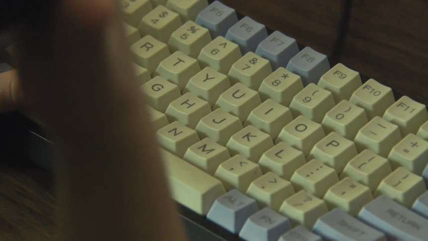 A persons hands typing on a mechanical keyboard placed on a desk