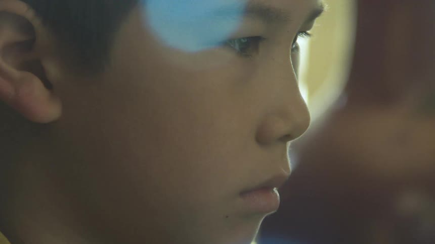Boy in closeup looking forward in a softly lit indoor setting