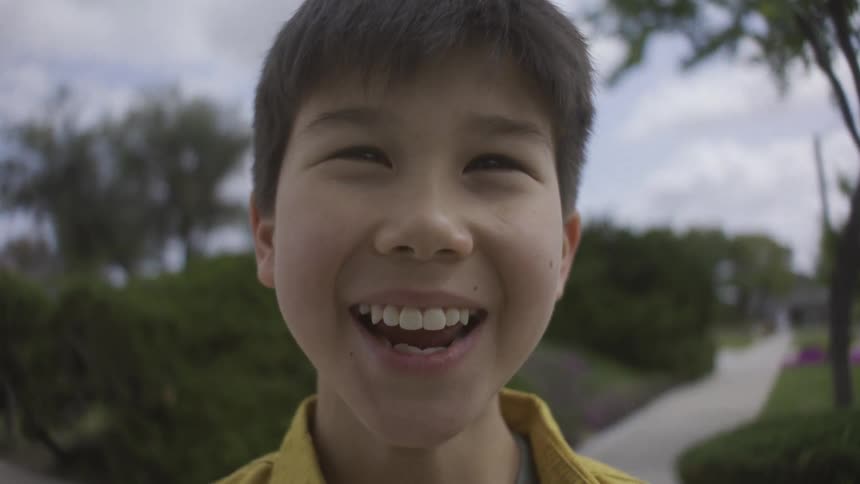 Child holding a handheld device on a residential sidewalk