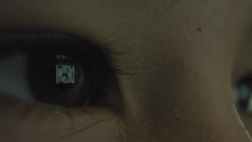 The reflection of a screen possibly a computer or television is visible in the pupilthe reflection shows what appears to be a small image or video of a person or figures on the screen moving briefly towards the middle and then back