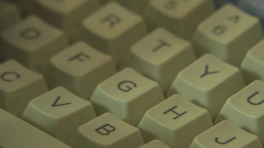 Closeup of hands typing on a vintage computer keyboard at an office desk