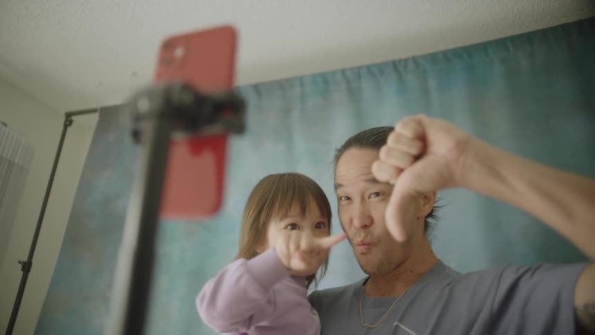 Father and daughter posing for a selfie with thumbs up in a makeshift studio