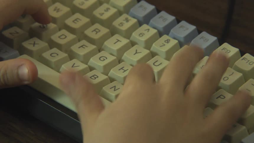The video features a closeup shot of a pair of hands likely a childs typing on a compact mechanical keyboard with a cream and light blue color schemethe hands move across the keys with some speed suggesting the person is actively engaged in typin