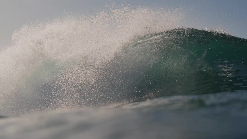 The wave crashes and sprays water
