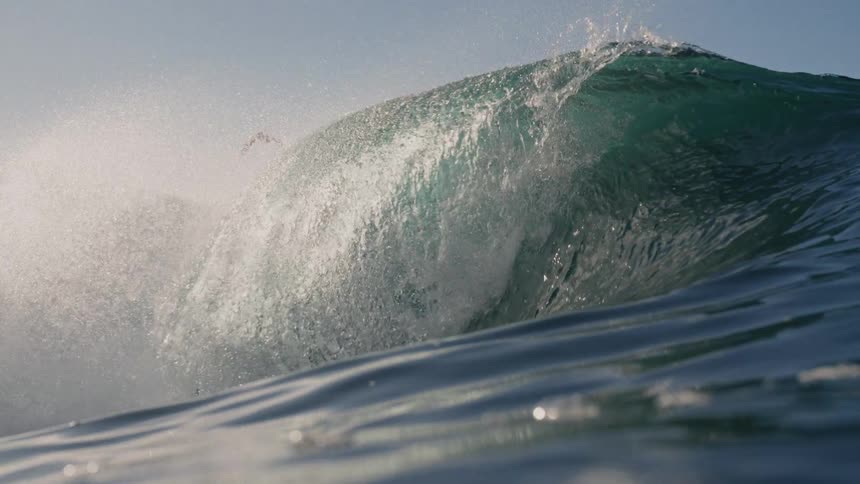 Large wave breaking with its crest highlighted by the light