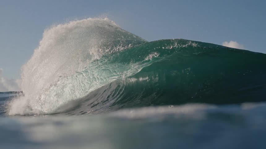 Wave splashes and curls as it rolls in and the view moves underwater
