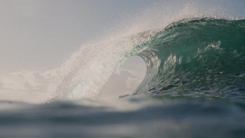 A large ocean wave curls and crashes eventually submerging the camera underwater