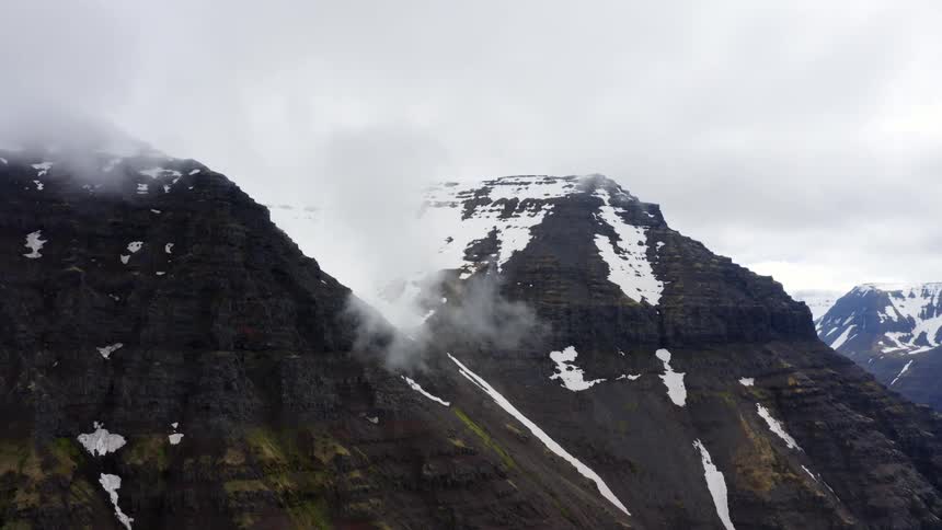 Snow on mountains with peaks high in the clouds