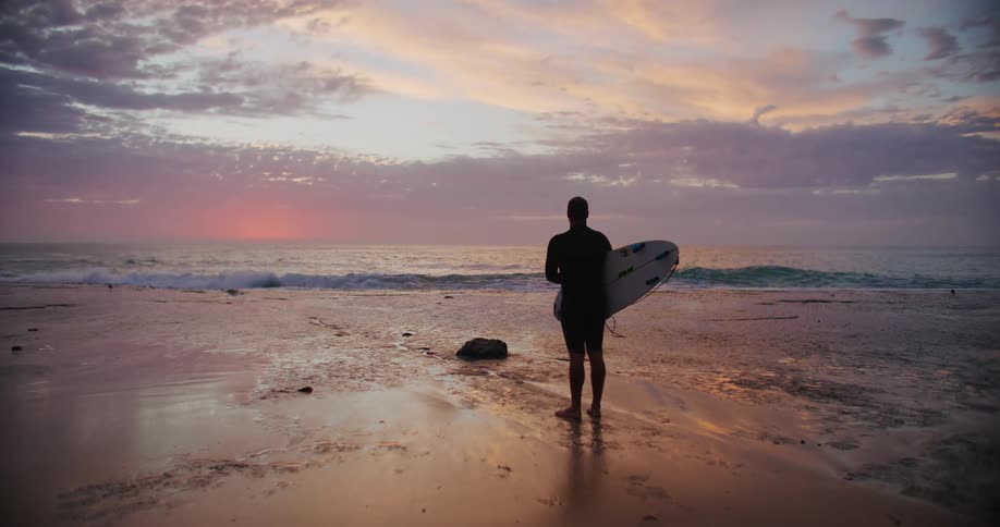 A person holding a surfboard on the beach