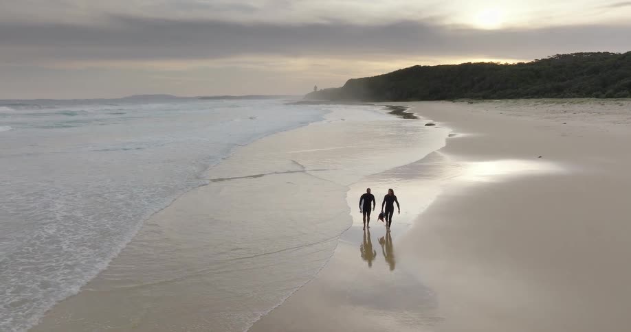 An aerial view of two people walking on a beach