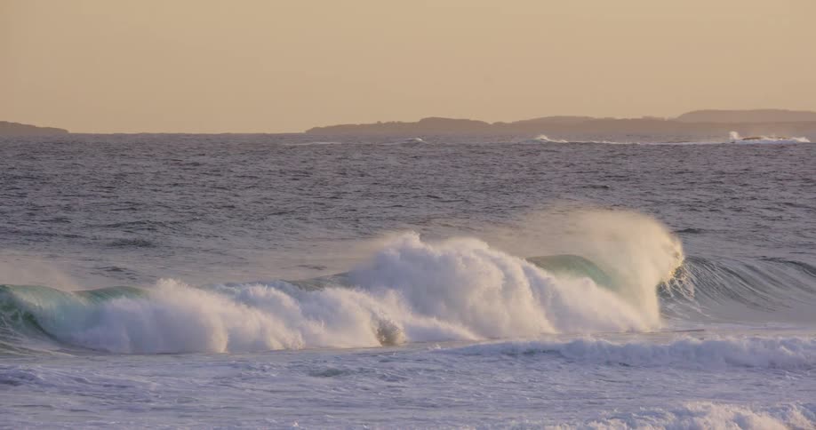 Waves splash and curl as they roll in to shore