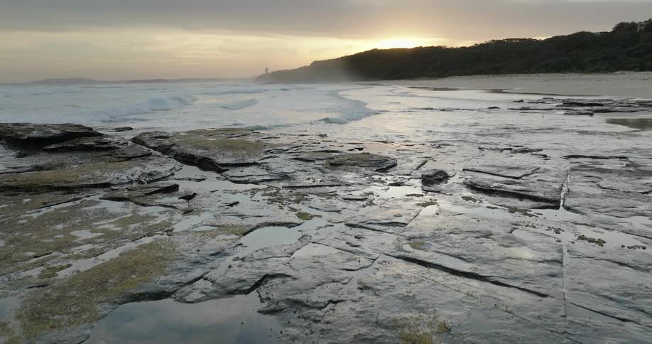 Rocky shoreline washed by gentle waves at sunrise