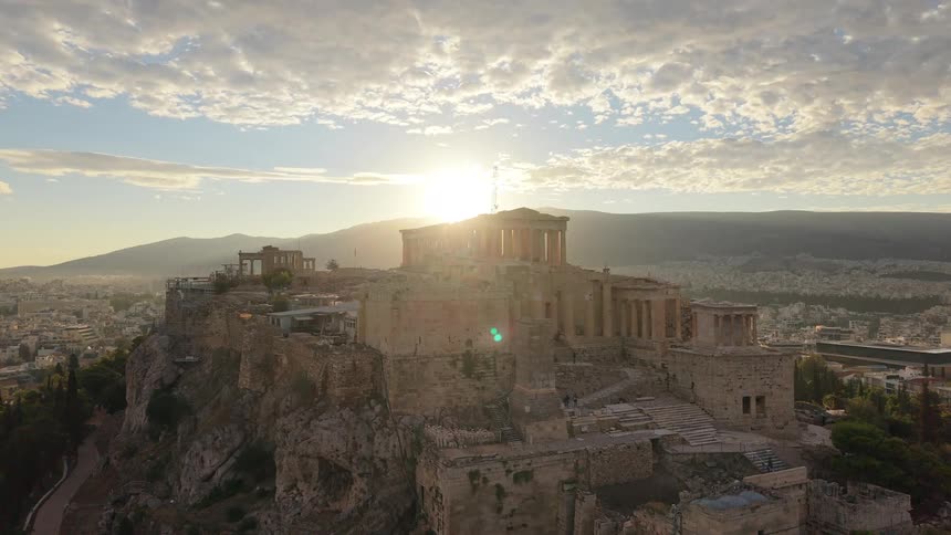 Acropolis of athens lit by the rising sun under a partly cloudy sky
