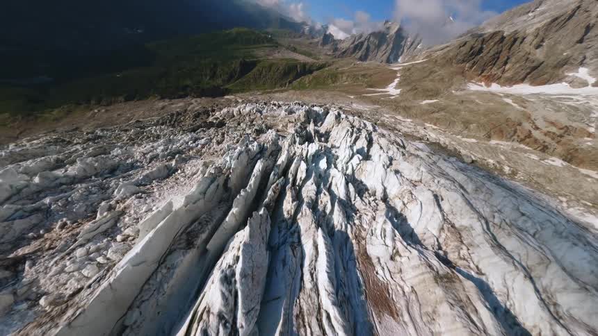 Ariel view of a vast glacier nestled beneath steep snow capped mountains