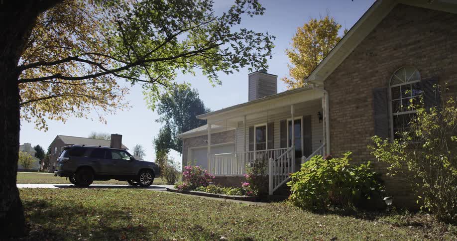 Onestory house with a porch and a car parked in the driveway