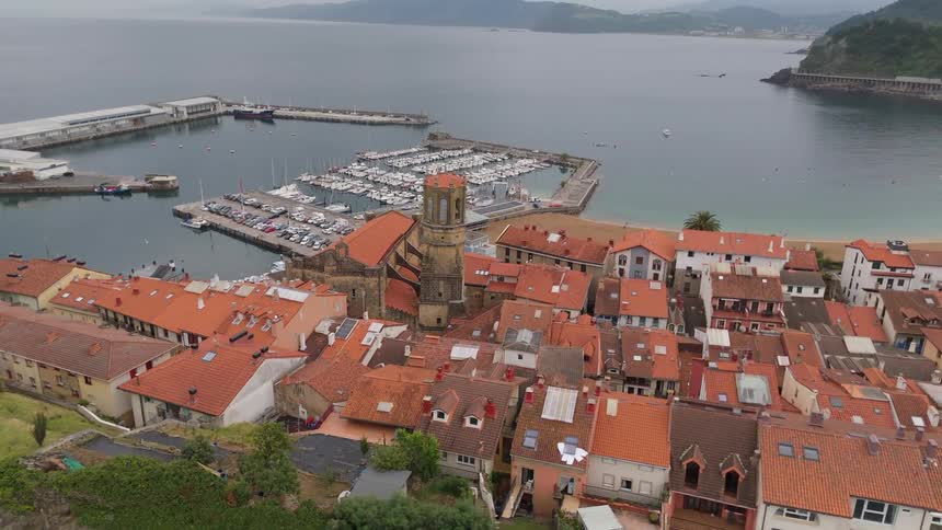 Aerial view of a coastal town perched on a cliff beside the sea overlooking a harbor