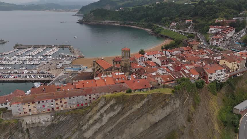 Coastal town with orange rooftops positioned on a cliff beside a marina