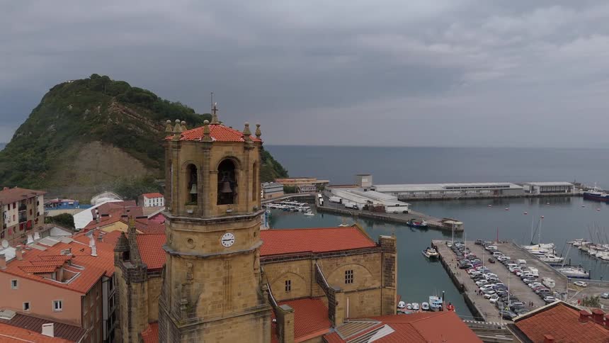 Aerial view of a coastal town with a historic church tower overlooking a harbor and marina