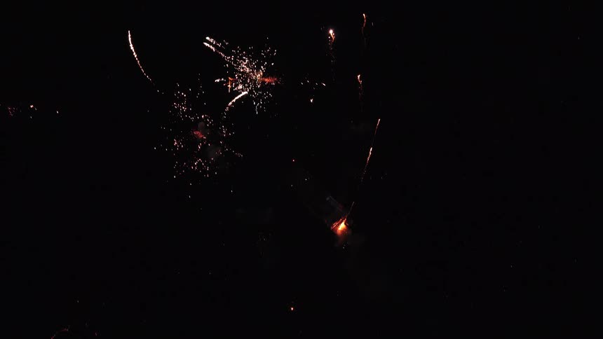The video shows a dark night sky illuminated by bright fireworksthe fireworks explode into bursts of gold and white light creating trails of sparks that fall and dissipate against the black background