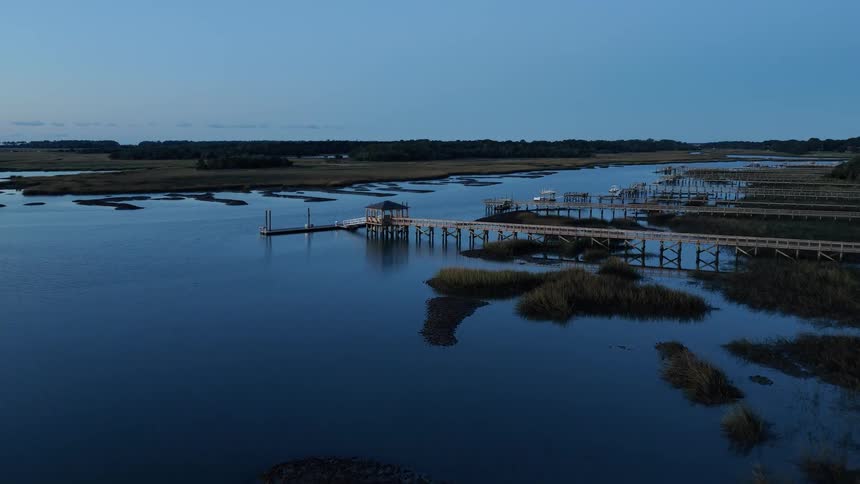 River with many marinas and boats attached to them with a natural landscape on the background outdoors during dusk or dawn