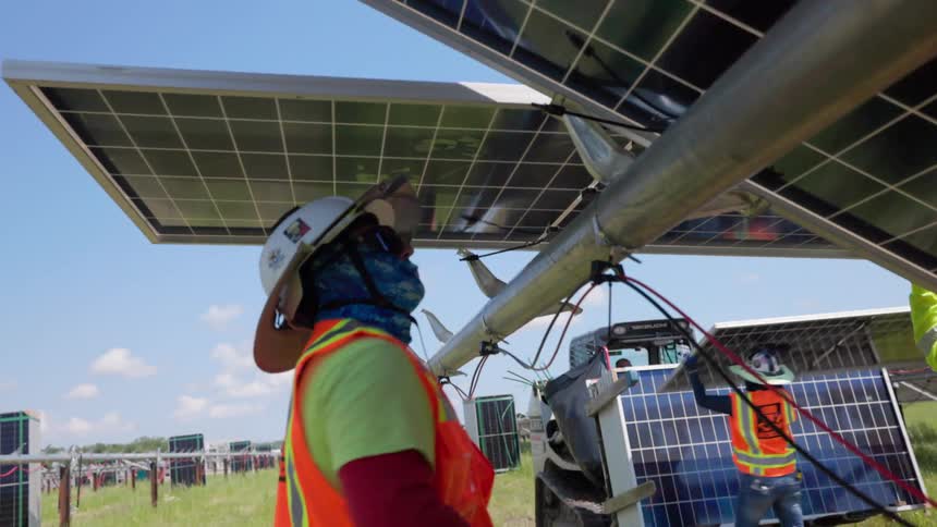 A group of workers putting up solar panels in a field