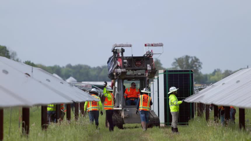Utility workers covering solar panels on a solar farm
